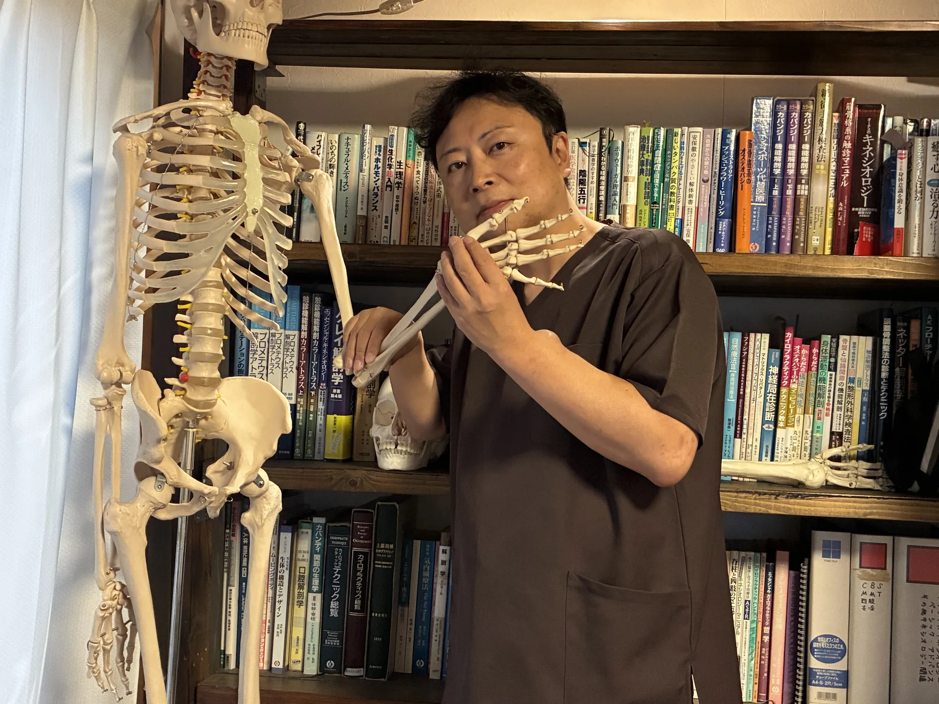 施術者の藤澤隆義が骨格模型を使って身体の構造を確認している様子